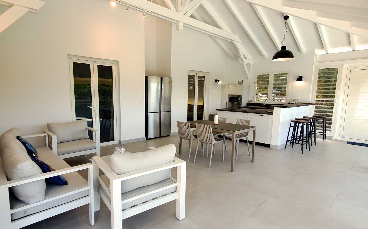 Terrasse couverte avec salon, table pour 4, coin cuisine et tablette bar.